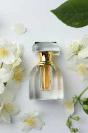 Photo of Bottle of perfume, jasmine flowers and green leaf on white background, flat lay