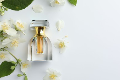 Photo of Bottle of perfume, jasmine flowers and green leaves on white background, flat lay. Space for text
