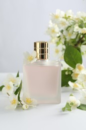 Photo of Bottle of perfume and jasmine flowers on white table
