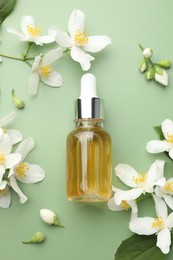 Photo of Essential oil and beautiful jasmine flowers on green background, flat lay
