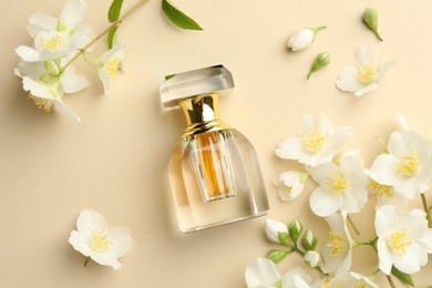 Photo of Bottle of perfume and beautiful jasmine flowers on beige background, flat lay