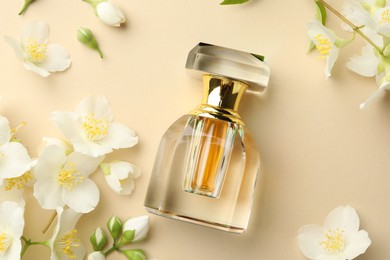 Photo of Bottle of perfume and beautiful jasmine flowers on beige background, flat lay