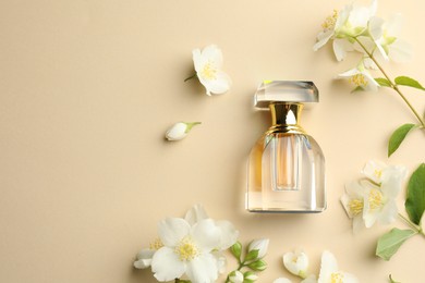 Photo of Bottle of perfume and beautiful jasmine flowers on beige background, flat lay. Space for text