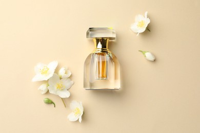 Photo of Bottle of perfume and beautiful jasmine flowers on beige background, flat lay