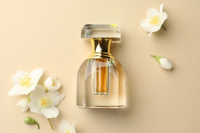 Photo of Bottle of perfume and beautiful jasmine flowers on beige background, flat lay