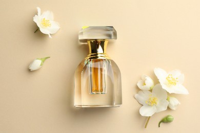 Photo of Bottle of perfume and beautiful jasmine flowers on beige background, flat lay