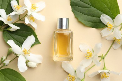 Photo of Bottle of perfume, beautiful jasmine flowers and green leaves on beige background, flat lay