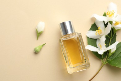Photo of Bottle of perfume, beautiful jasmine flowers and green leaves on beige background, flat lay. Space for text