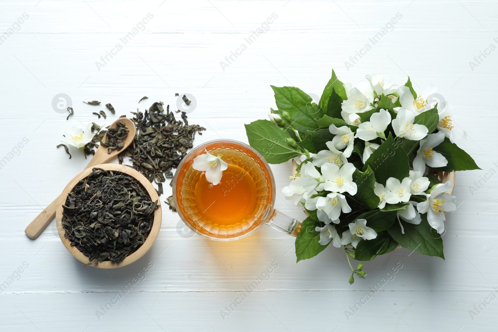 Aromatic jasmine tea in glass cup, flowers and leaves on white wooden table, flat lay Photo of Aromatic jasmine tea in glass cup, flowers and leaves on white wooden table, flat lay