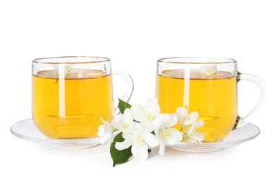 Photo of Aromatic jasmine tea in glass cups, flowers and green leaves isolated on white