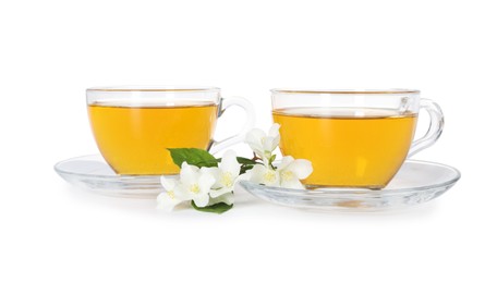 Photo of Aromatic jasmine tea in glass cups, flowers and green leaves isolated on white