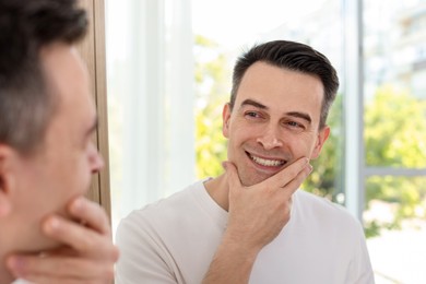 Photo of Smiling man after shaving near mirror at home