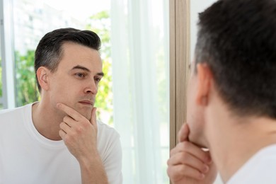 Photo of Handsome man after shaving near mirror at home