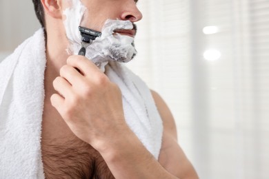 Photo of Man shaving with razor at home, closeup. Space for text