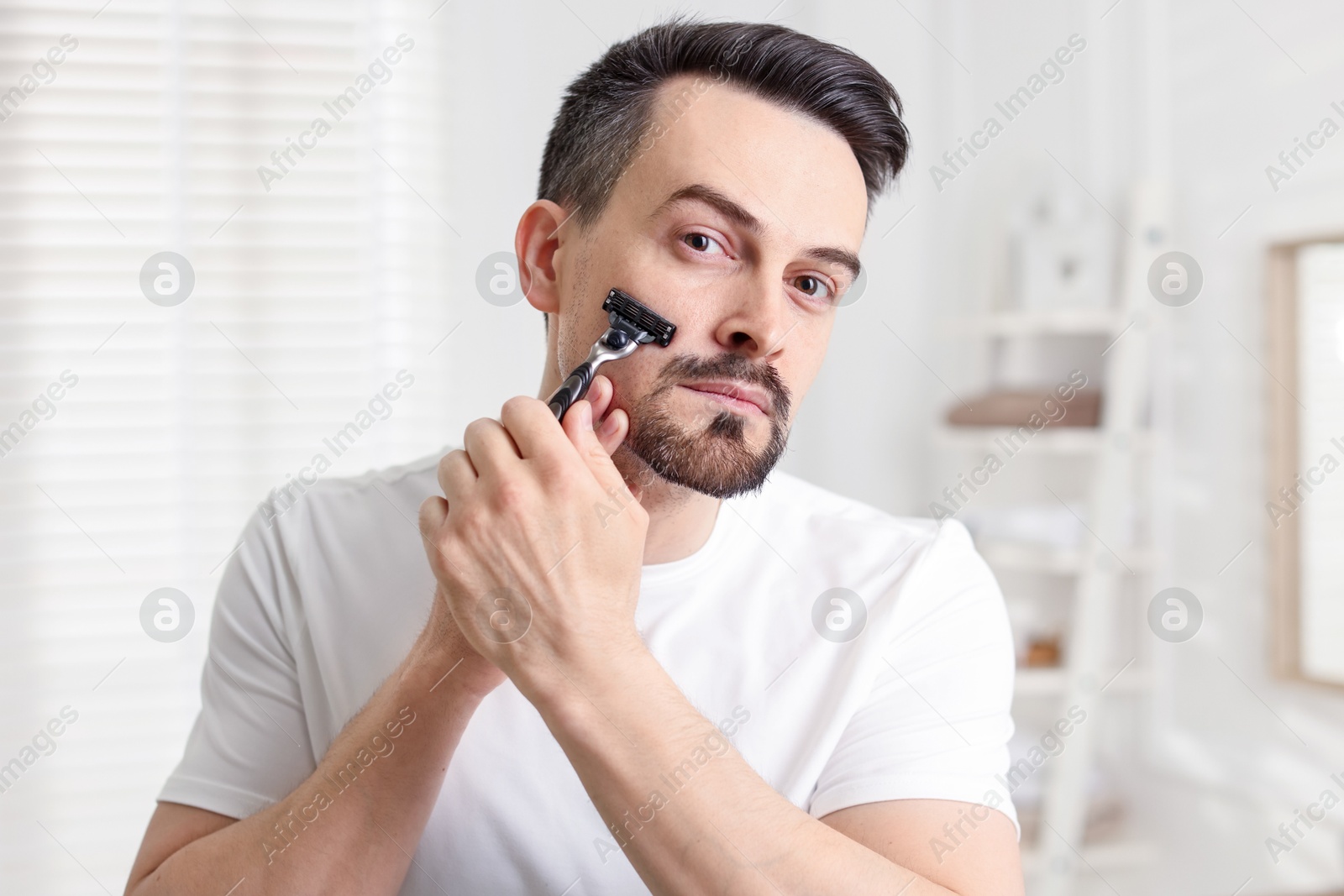 Handsome man shaving with razor at home Photo of Handsome man shaving with razor at home