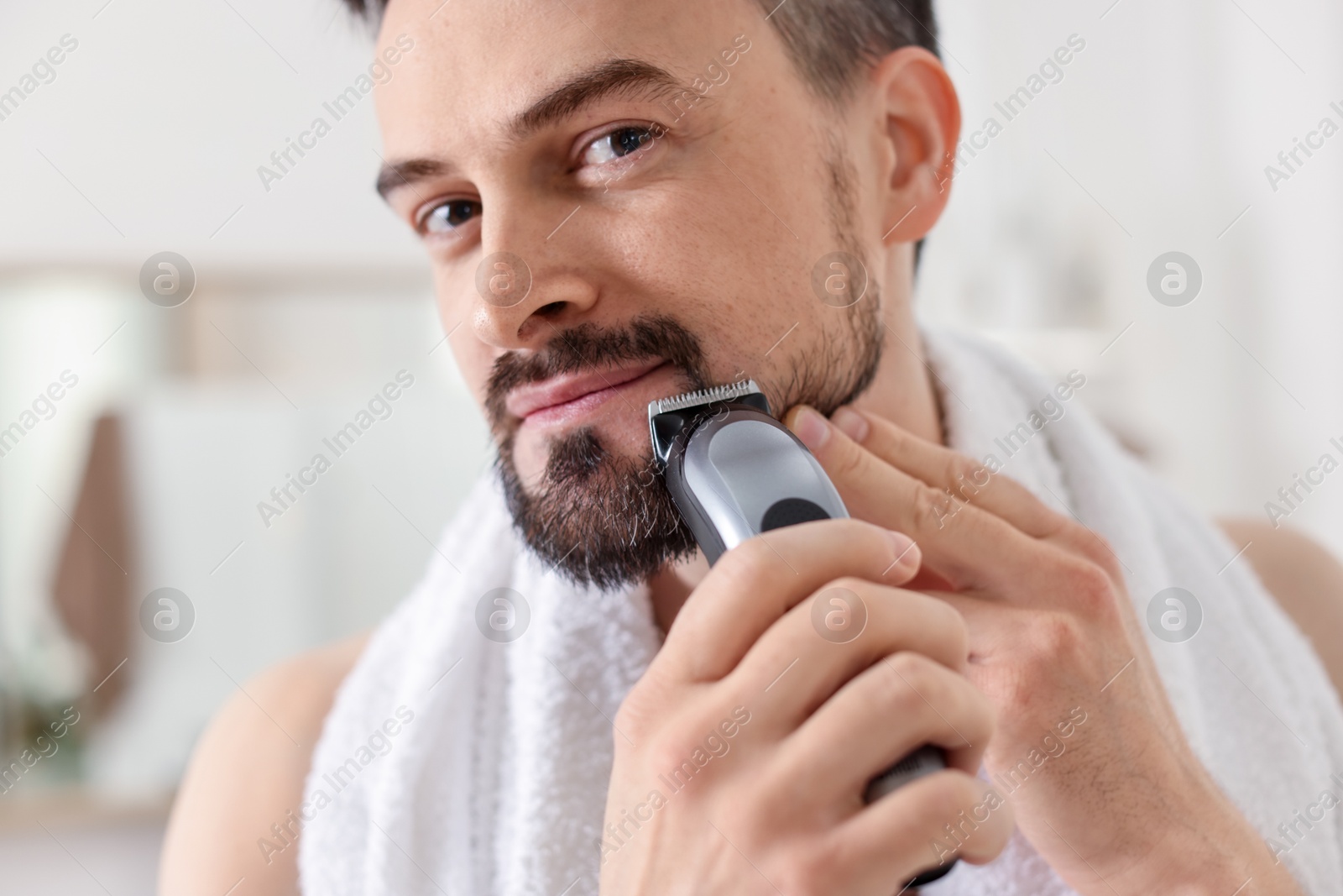Handsome man shaving with trimmer at home, closeup Photo of Handsome man shaving with trimmer at home, closeup