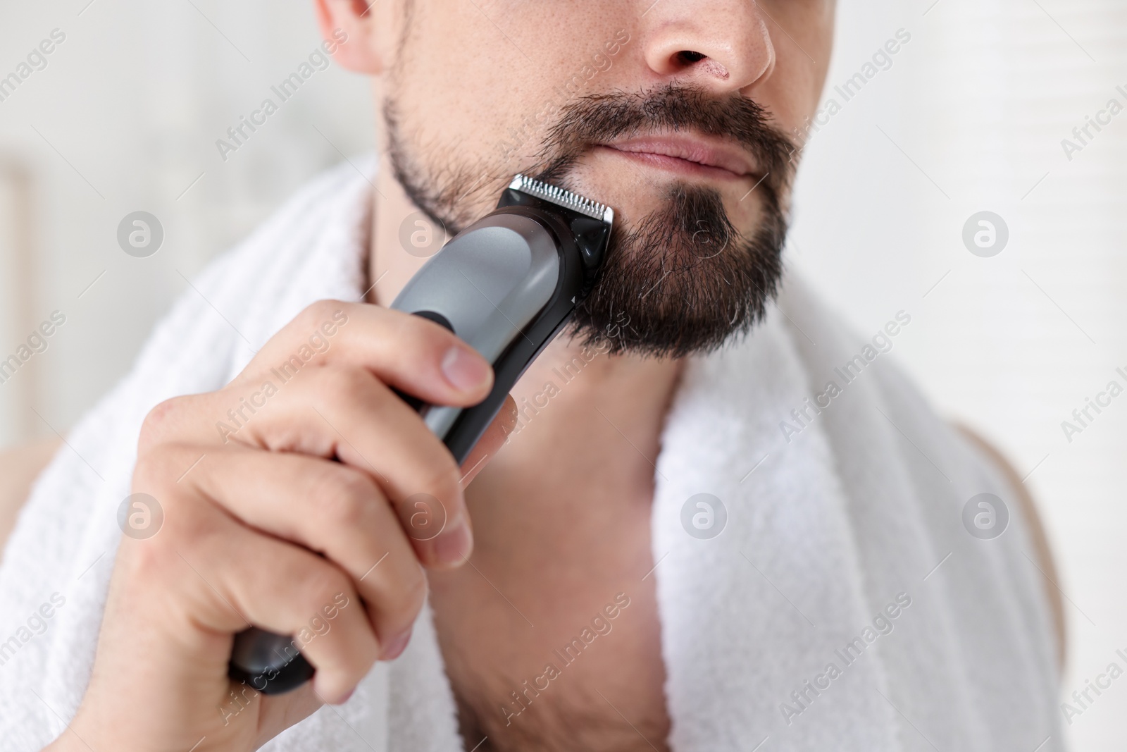 Man shaving with trimmer at home, closeup Photo of Man shaving with trimmer at home, closeup