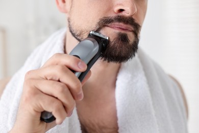 Photo of Man shaving with trimmer at home, closeup