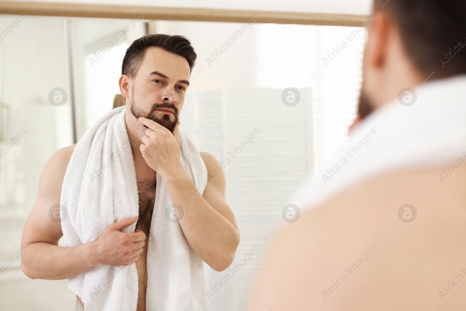 Handsome man before shaving looking at mirror in bathroom Photo of Handsome man before shaving looking at mirror in bathroom