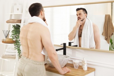 Photo of Handsome man before shaving looking at mirror in bathroom