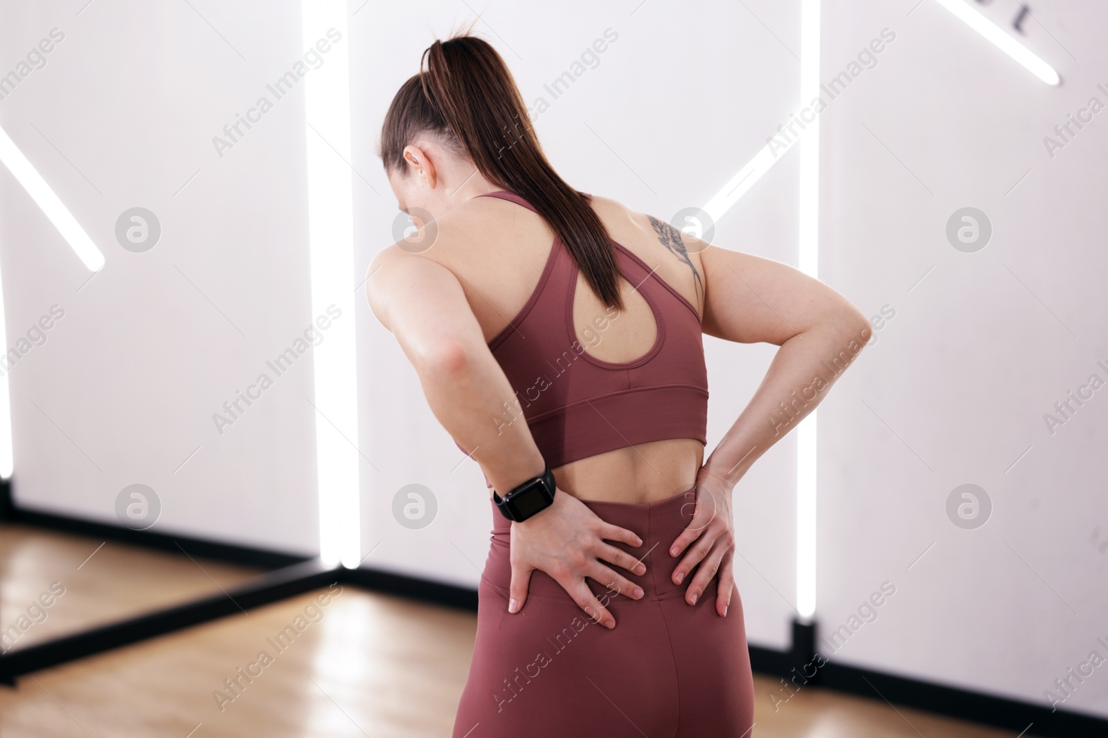 Photo of Sportswoman with back injury in fitness studio