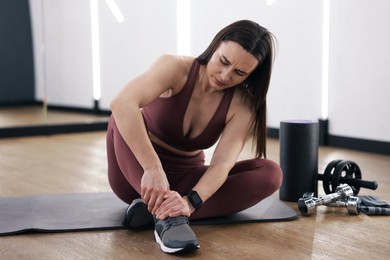 Photo of Sportswoman with leg injury in fitness studio