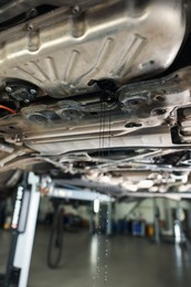 Photo of Dirty old motor oil dripping from car engine in workshop, closeup