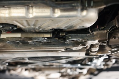 Photo of Dirty old motor oil dripping from car engine in workshop, closeup