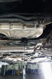 Photo of Dirty old motor oil dripping from car engine in workshop, closeup