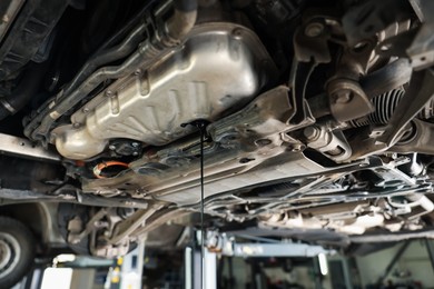 Photo of Dirty old motor oil dripping from car engine in workshop, closeup