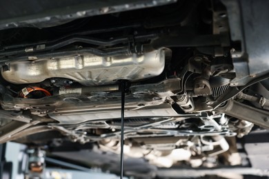 Photo of Dirty old motor oil dripping from car engine in workshop, closeup