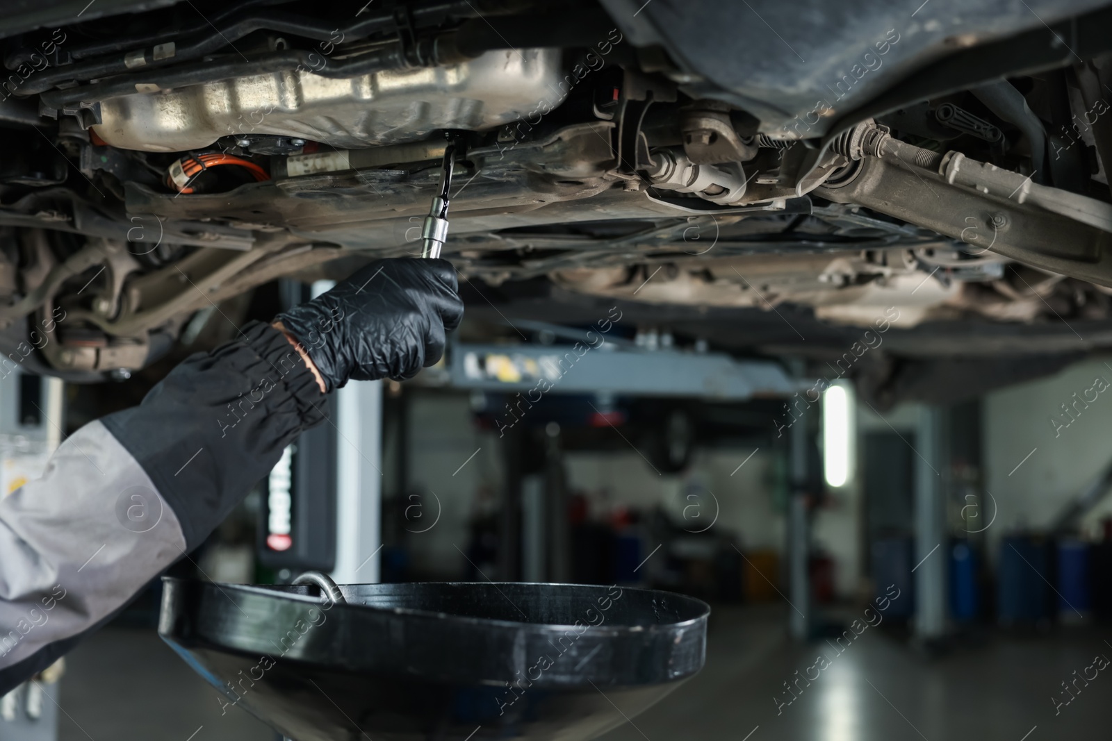 Worker removing dirty old motor oil from car engine, closeup Photo of Worker removing dirty old motor oil from car engine, closeup
