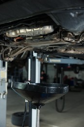 Photo of Dirty old motor oil dripping from car engine in workshop, closeup