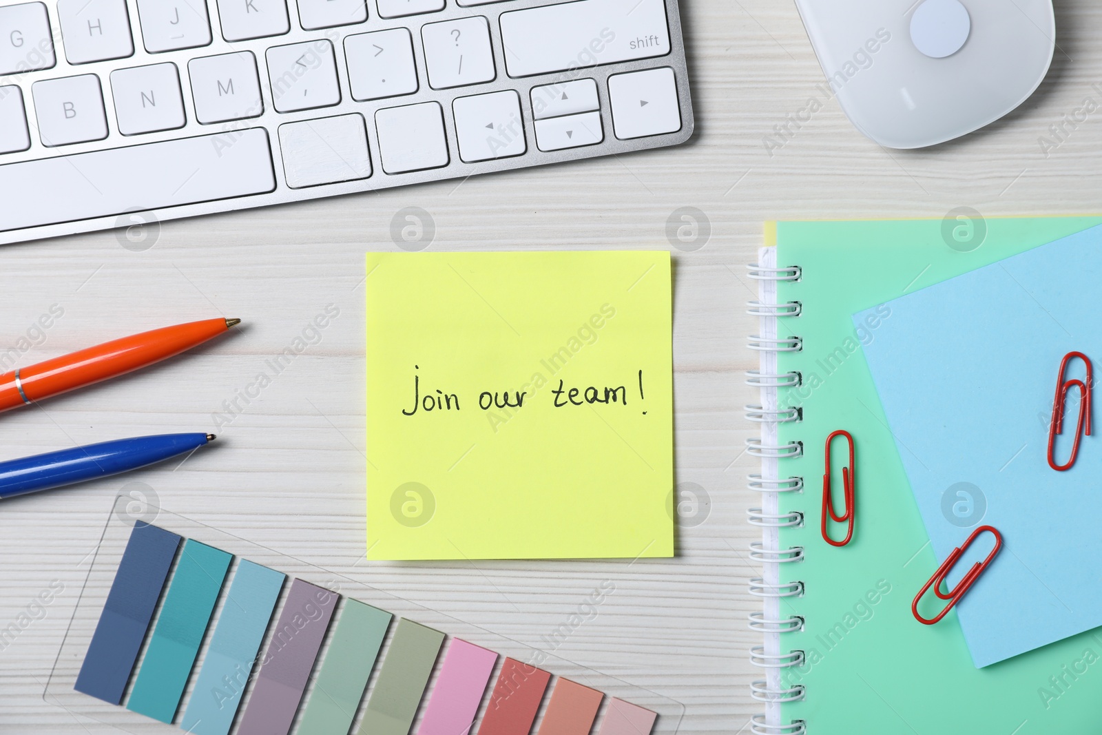 Photo of Paper note with phrase Join Our Team, keyboard and stationery on white wooden table, flat lay