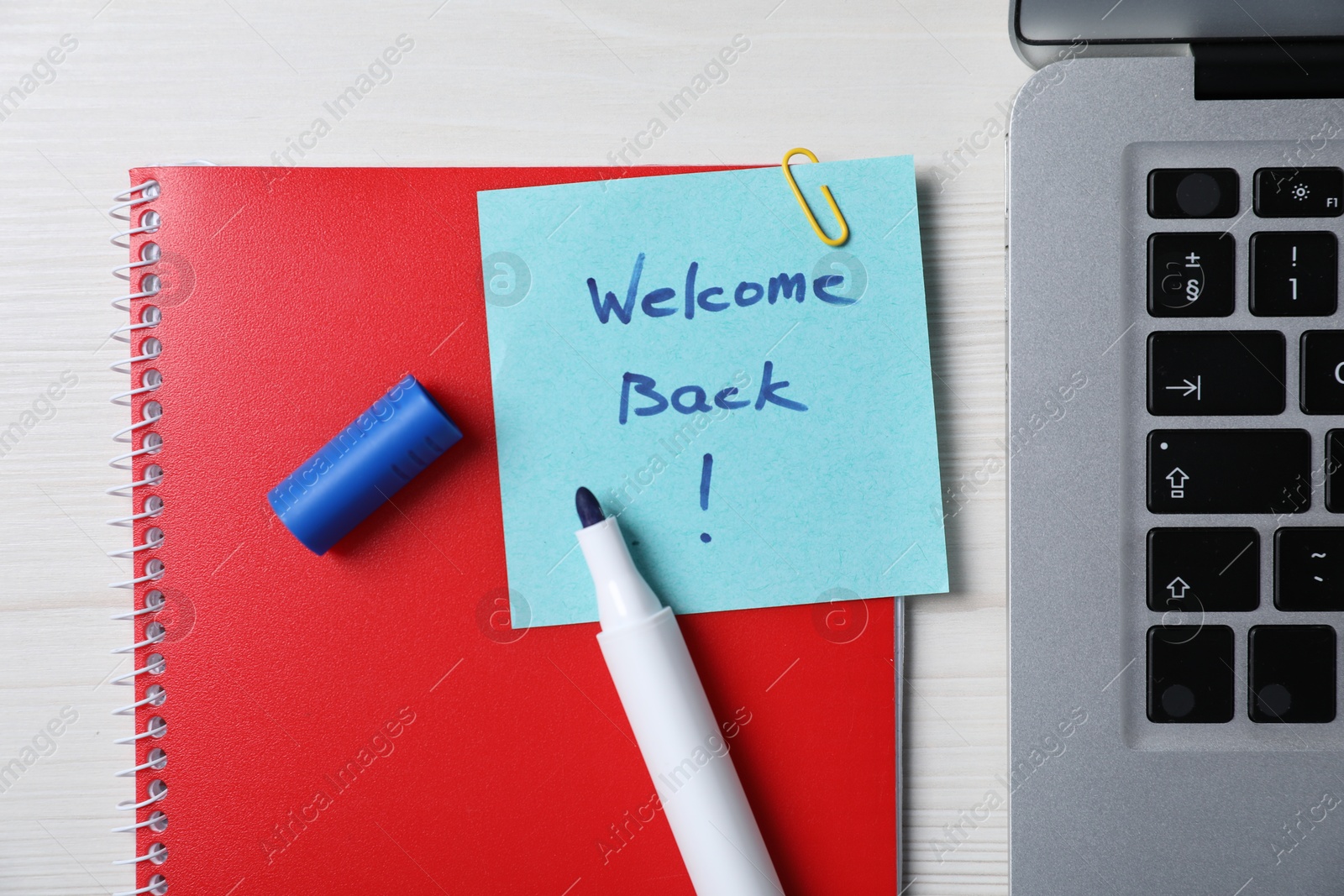 Paper note with phrase Welcome Back, laptop and stationery on white wooden table, flat lay Photo of Paper note with phrase Welcome Back, laptop and stationery on white wooden table, flat lay