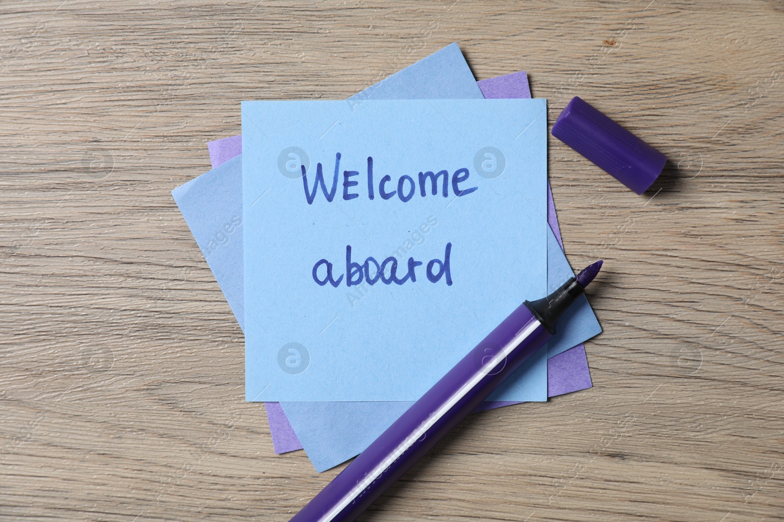 Paper note with phrase Welcome Aboard and felt tip pen on wooden table, top view Photo of Paper note with phrase Welcome Aboard and felt tip pen on wooden table, top view