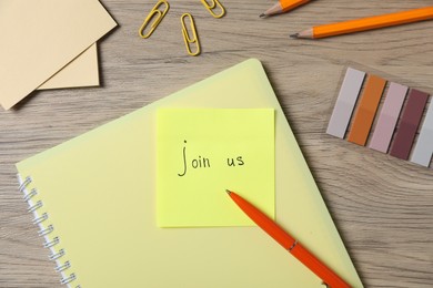 Photo of Paper note with phrase Join Us and stationery on wooden table, flat lay