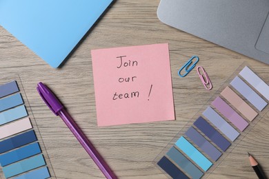 Photo of Paper note with phrase Join Our Team, laptop and stationery on wooden table, flat lay