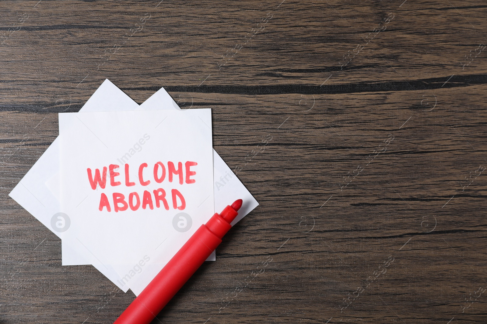 Paper note with phrase Welcome Aboard and felt tip pen on wooden table, top view. Space for text Photo of Paper note with phrase Welcome Aboard and felt tip pen on wooden table, top view. Space for text