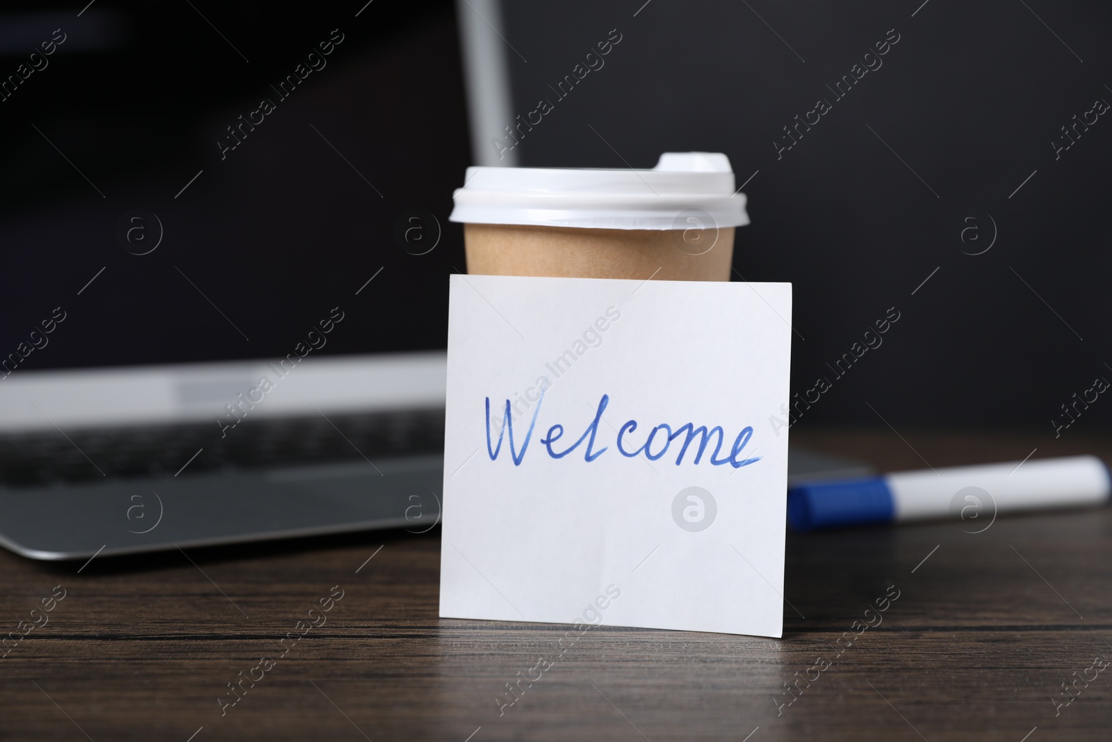 Paper note with word Welcome, cup of coffee, pen and laptop on wooden table Photo of Paper note with word Welcome, cup of coffee, pen and laptop on wooden table