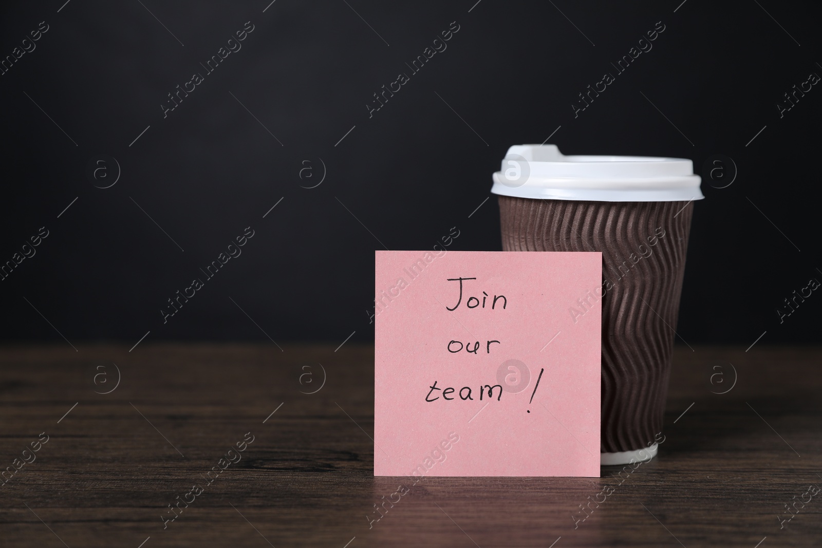 Photo of Paper note with phrase Join Our Team and cup of coffee on wooden table. Space for text