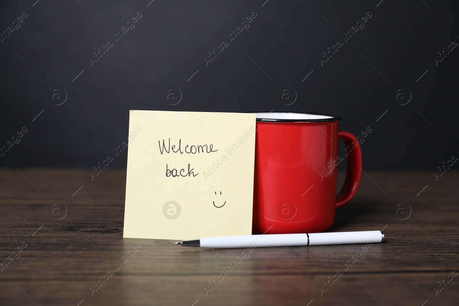 Paper note with phrase Welcome Back, pen and cup of coffee on wooden table Photo of Paper note with phrase Welcome Back, pen and cup of coffee on wooden table
