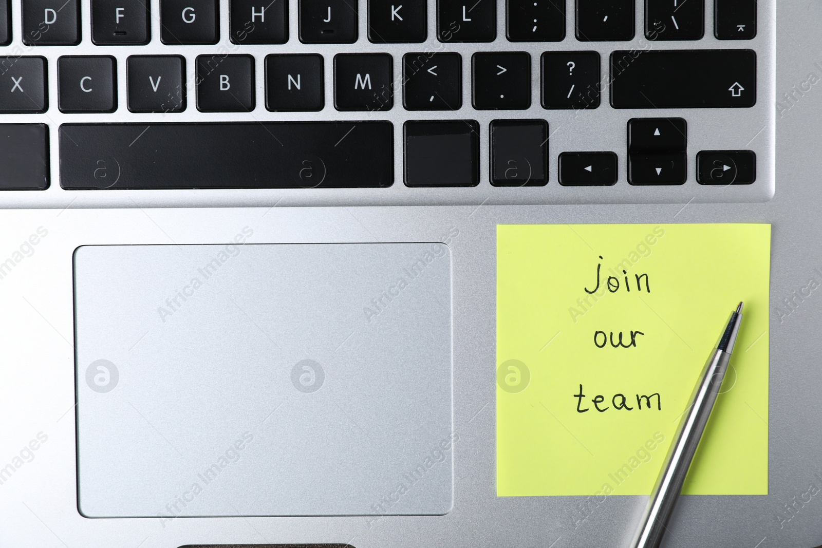 Paper note with phrase Join Our Team and pen on laptop, top view Photo of Paper note with phrase Join Our Team and pen on laptop, top view