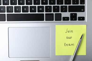 Photo of Paper note with phrase Join Our Team and pen on laptop, top view