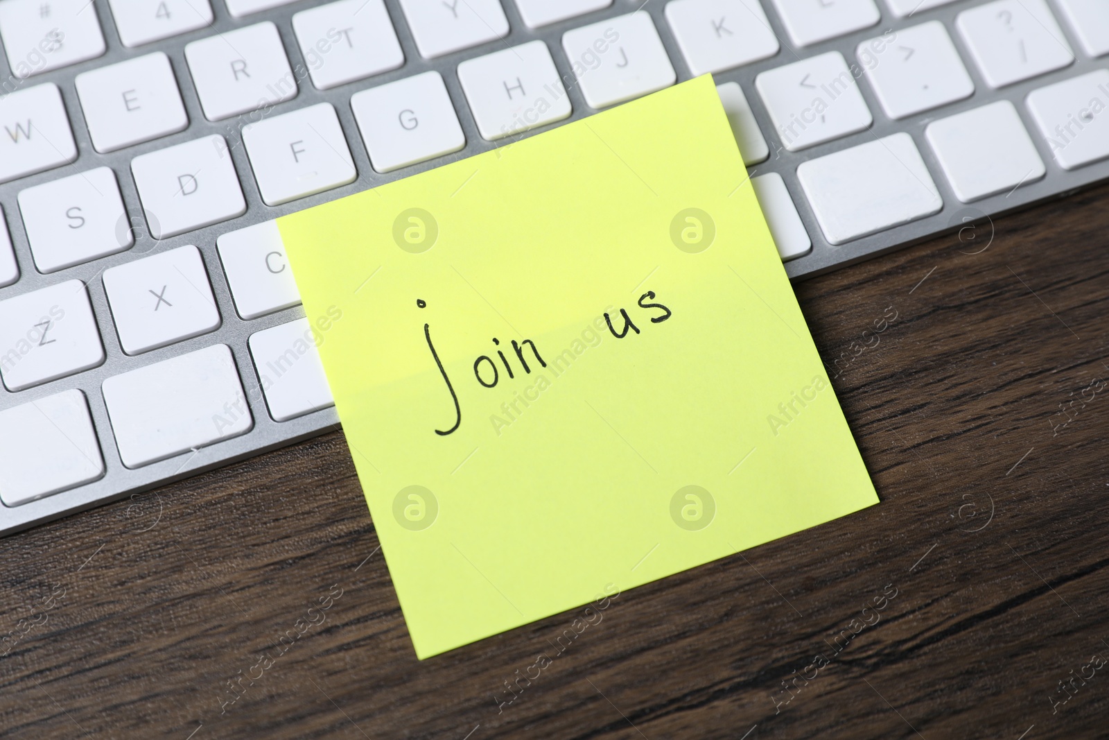 Paper note with phrase Join Us and keyboard on wooden table, closeup Photo of Paper note with phrase Join Us and keyboard on wooden table, closeup