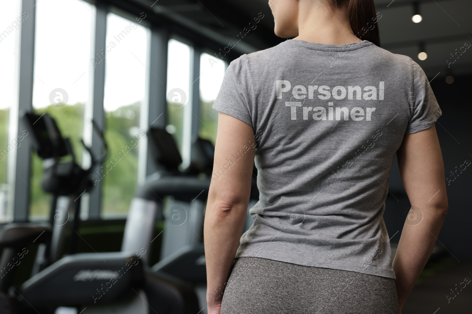 Personal trainer wearing t-shirt with inscription in gym, closeup. Back view Image of Personal trainer wearing t-shirt with inscription in gym, closeup. Back view