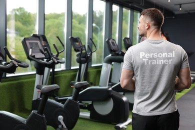 Image of Personal trainers wearing t-shirt with inscription in gym. Back view