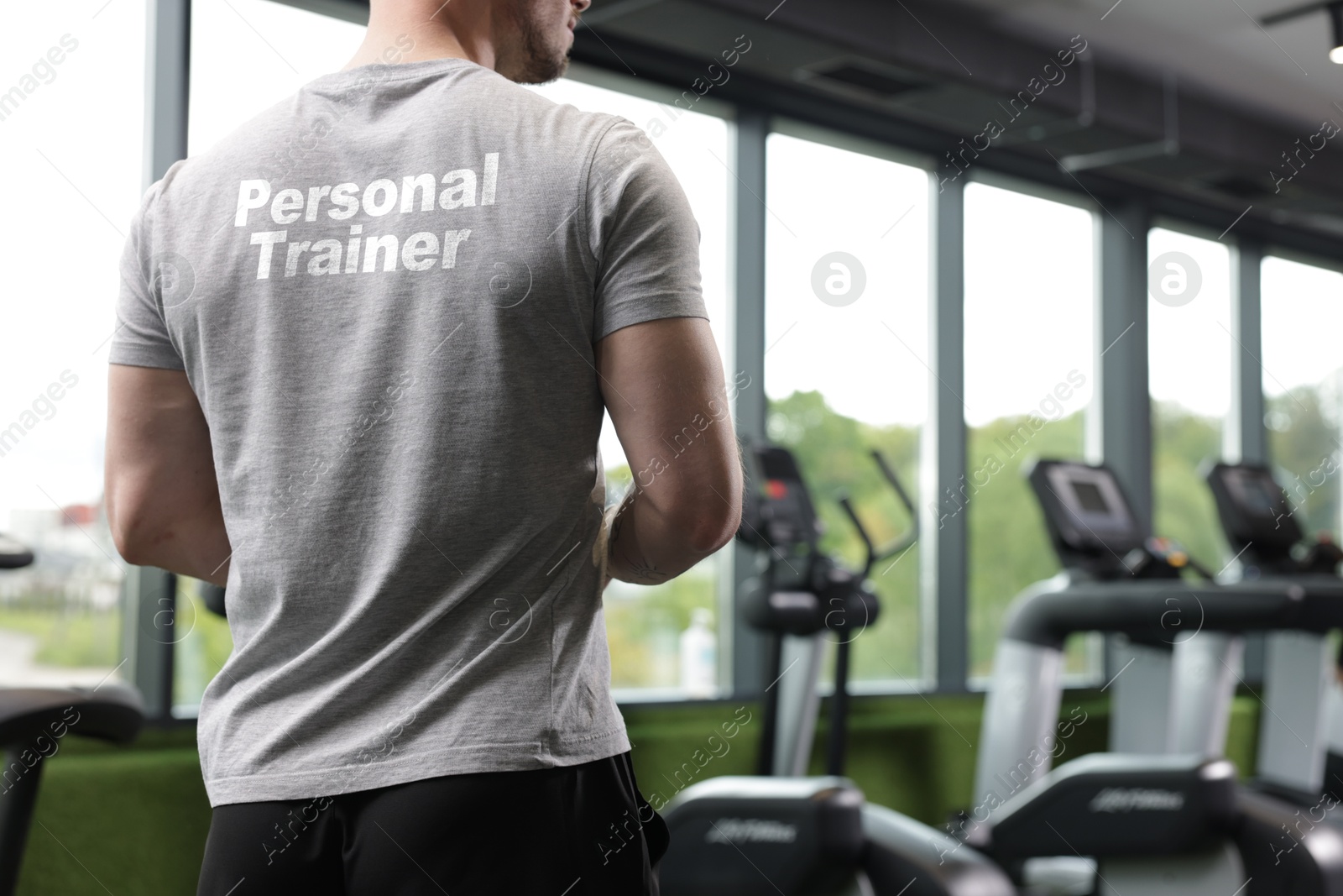 Personal trainer wearing t-shirt with inscription in gym, closeup. Back view Image of Personal trainer wearing t-shirt with inscription in gym, closeup. Back view