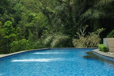 Photo of Outdoor swimming pool with clear water and green plants
