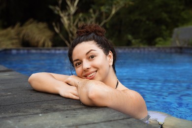 Photo of Happy woman relaxing in swimming pool outdoors